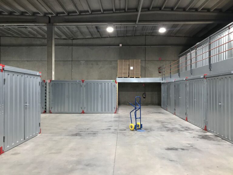 Nave de guardamuebles con módulos metálicos cerrados y una carretilla